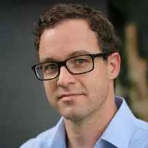 Dr. med. Grupp mit Brille und hellblauem Hemd vor unscharfem Hintergrund.