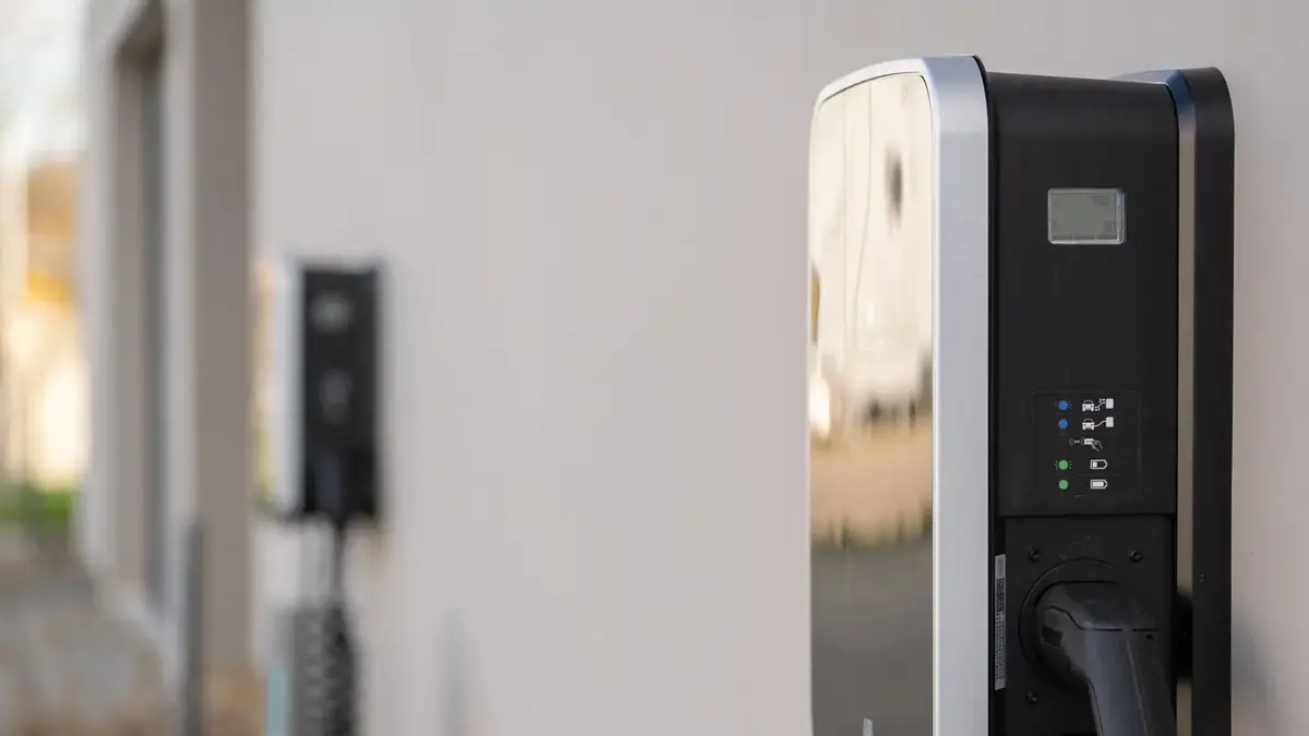 Multiple electric vehicle wall chargers mounted on an outdoor building wall.