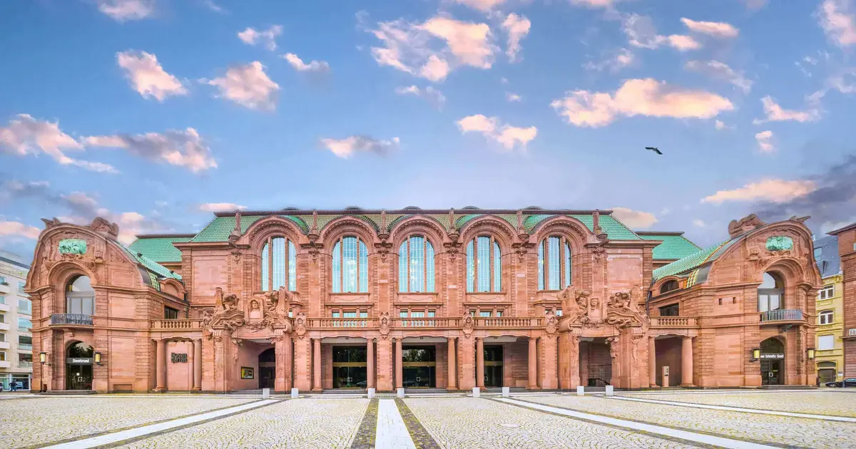 Frontansicht des Nationaltheaters Mannheim mit eindrucksvoller historischer Sandsteinfassade unter einem malerischen Abendhimmel.