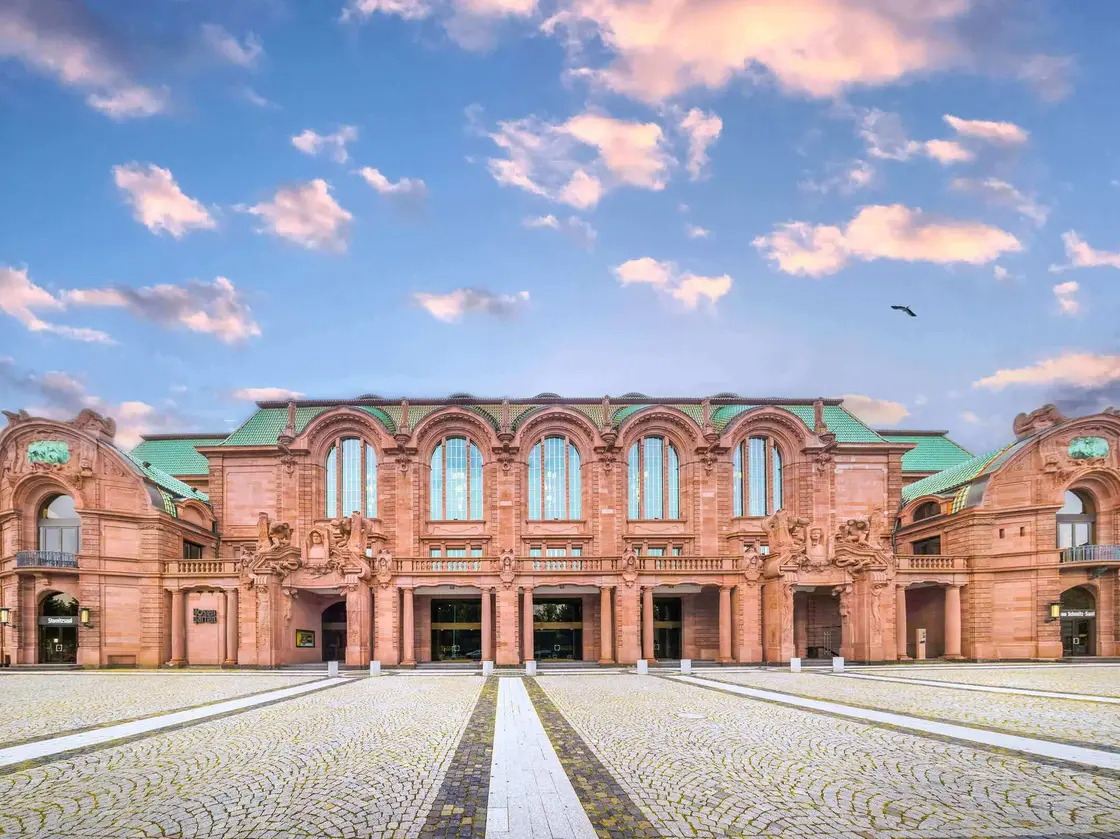 Mannheim-Nationaltheater-Fassade-Abendstimmung.jpg Frontansicht des Nationaltheaters Mannheim mit eindrucksvoller historischer Sandsteinfassade unter einem malerischen Abendhimmel.