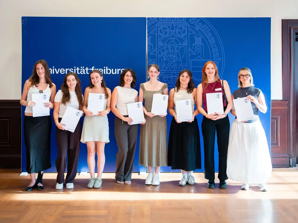 Group photo of scholarship recipients standing in front of a University of Freiburg presentation wall. The image represents academic support, talent development, educational achievement, and participation in a scholarship program.
