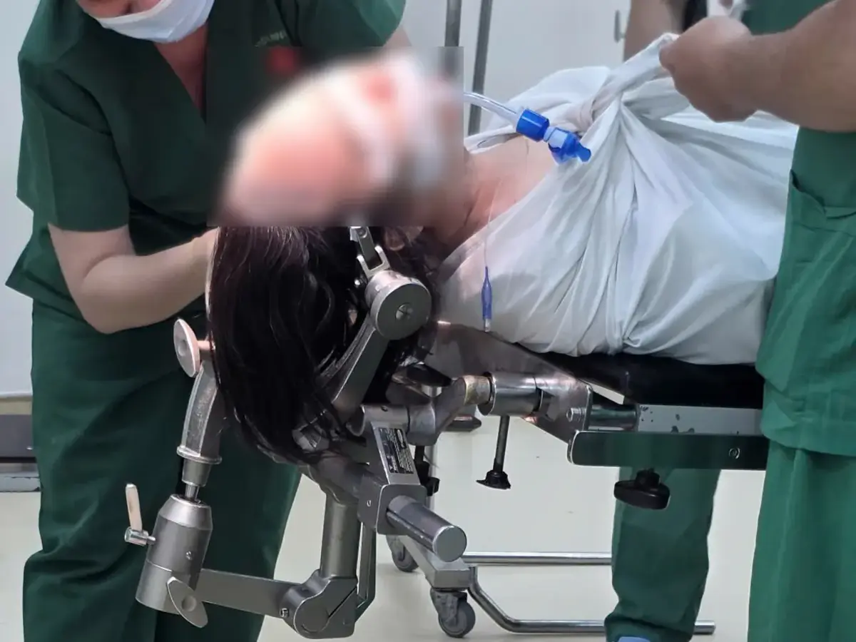 Medical personnel position a patient on an adjustable operating table in a clinical treatment room.