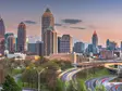 Skyline von Atlanta, USA, bei Sonnenuntergang mit beleuchteten Hochhäusern und fließendem Abendverkehr auf den geschwungenen Highways im Vordergrund.