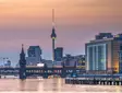 Berliner Fernsehturm und Oberbaumbrücke bei Sonnenuntergang über der Spree.
