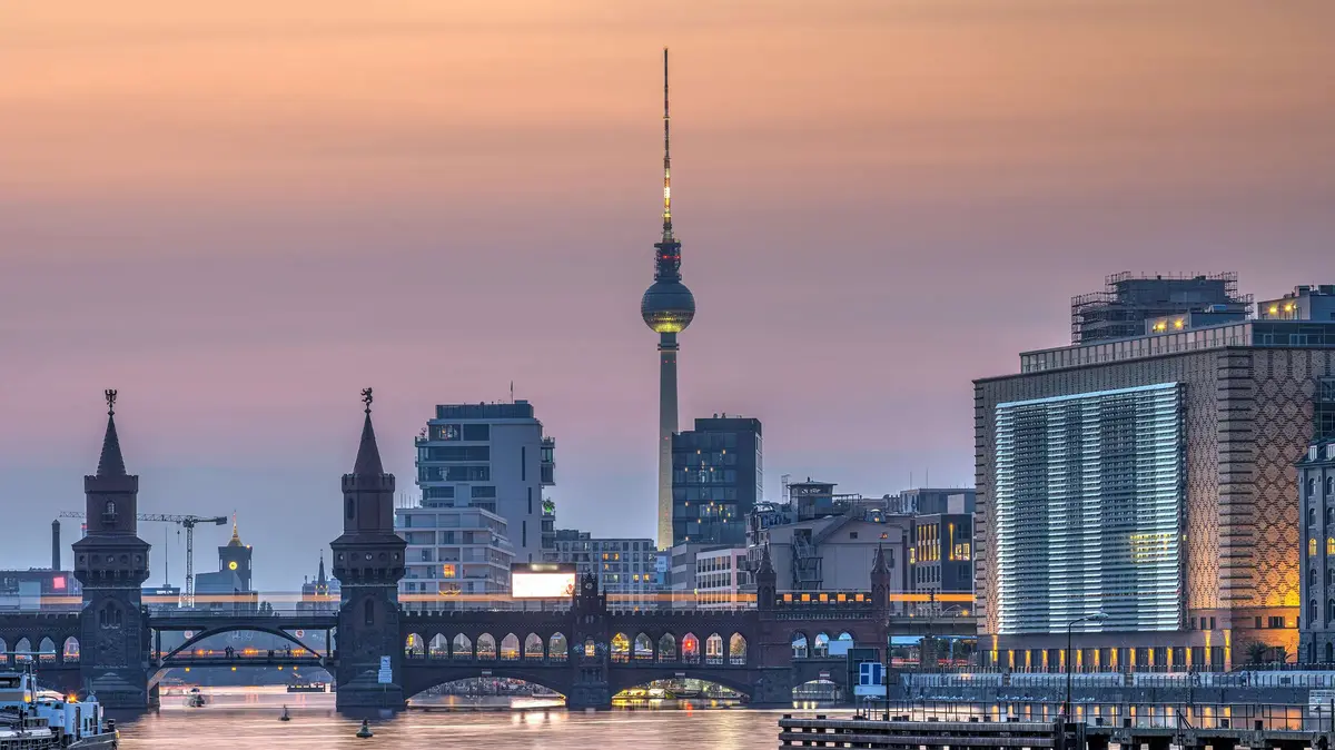Berlin TV Tower and Oberbaum Bridge at sunset above the River Spree.