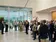 Eine größere Besuchergruppe steht im Foyer und hört einem Vortragenden im modernen Firmengebäude zu.