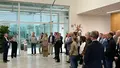 Eine größere Besuchergruppe steht im Foyer und hört einem Vortragenden im modernen Firmengebäude zu.