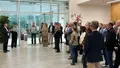 Eine größere Besuchergruppe steht im Foyer und hört einem Vortragenden im modernen Firmengebäude zu.