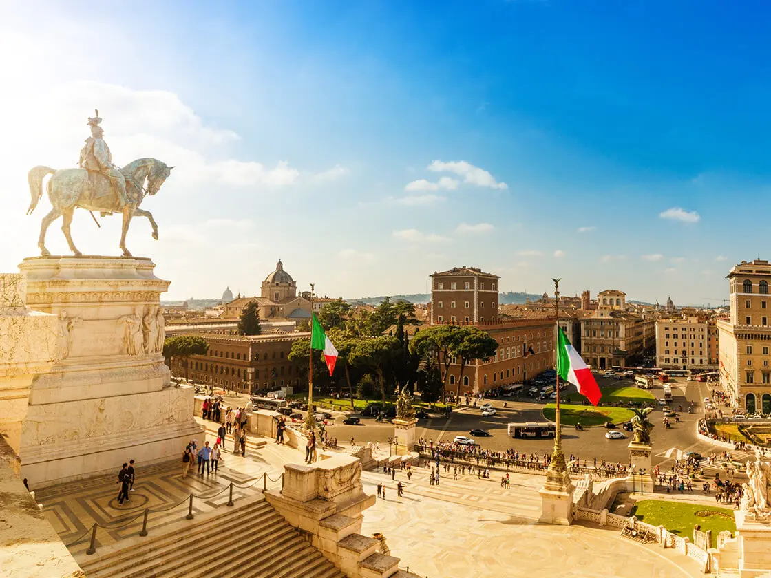 Panoramablick über Rom mit Reiterdenkmal am Vittorio‑Emanuele‑II.‑Monument, italienischen Flaggen und historischer Altstadt