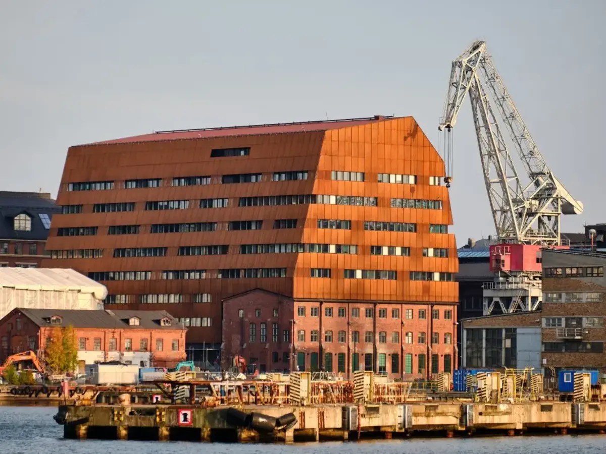Modern brick building at a waterfront location with harbor and city skyline.