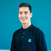 Porträt von Henry, Auszubildender zum Industriemechaniker (m/w/d) bei Sutter Medizintechnik Schweiz, vor blauem Hintergrund