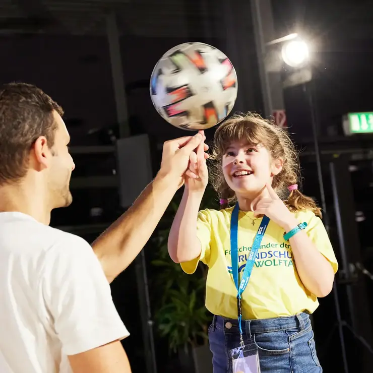 Person balanciert einen Ball während einer interaktiven Team-Challenge auf einer Veranstaltung.