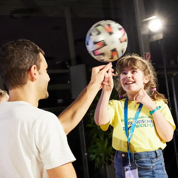 Participant balancing a ball during an interactive team challenge at an event.