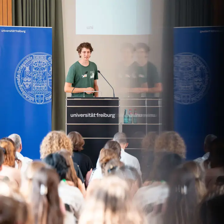 Vortrag eines Teilnehmenden bei einer Veranstaltung der Universität Freiburg vor großem Publikum. Die Aufnahme steht für akademischen Austausch, studentisches Engagement und die aktive Mitgestaltung von Stipendien- und Förderprogrammen.