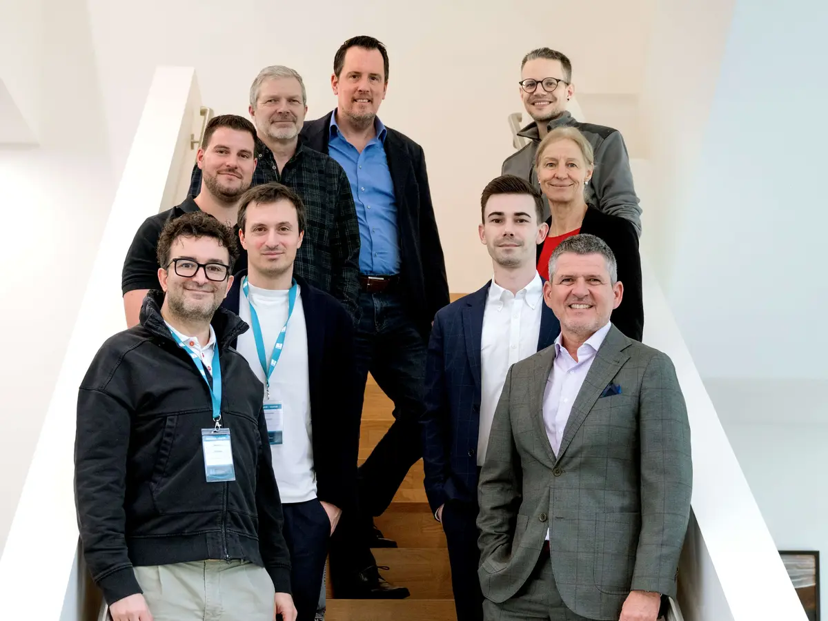 Gruppe von Mitarbeitenden auf einer Treppe in einem modernen Büro- und Unternehmensgebäude.