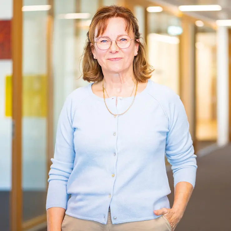 Frau mit Brille und hellblauer Strickjacke steht im Büroflur bei Sutter Medizintechnik – Mitarbeiterin der Verwaltung.