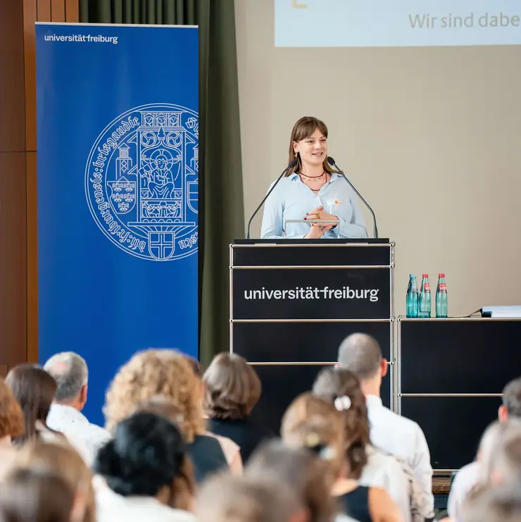 Speaker presenting at a University of Freiburg event focused on scholarships and academic engagement. The image highlights educational support, talent development, and knowledge exchange in a higher education setting.