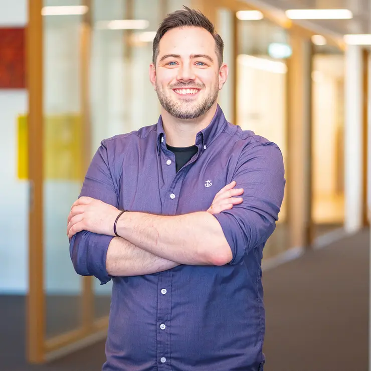 Patric Schlegel steht lächelnd im Flur von Sutter Medizintechnik – Einkauf bei Sutter Medizintechnik. 