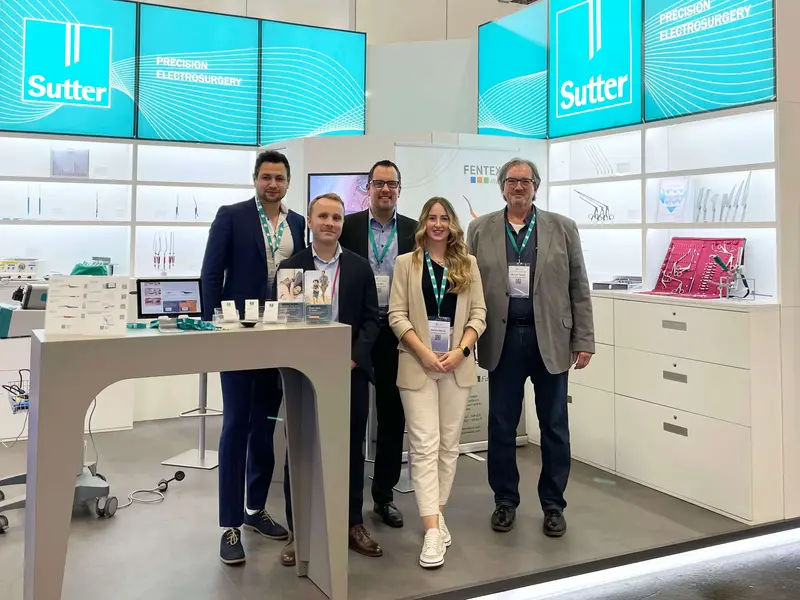 Sutter-DGHNO-Messestand-Team Fünf Personen am Sutter Messestand mit elektrochirurgischen Instrumenten auf einer Fachmesse.