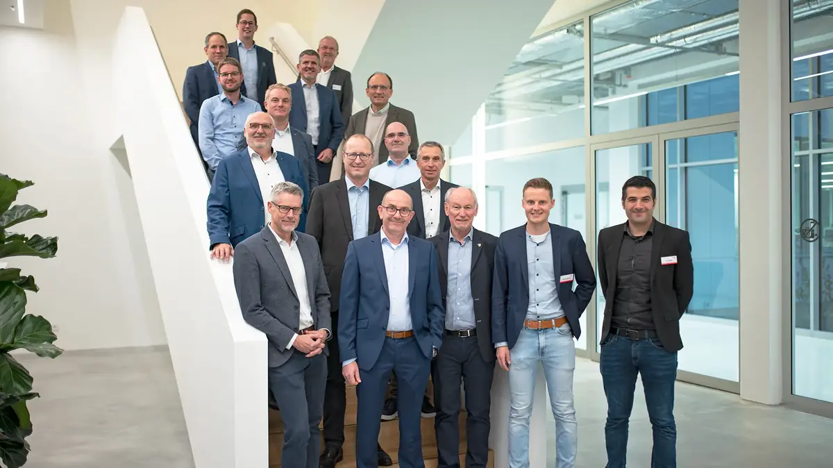 Gruppenfoto von Teilnehmenden des wvib Clusters Medizintechnik auf einer Treppe in einem modernen Firmengebäude.