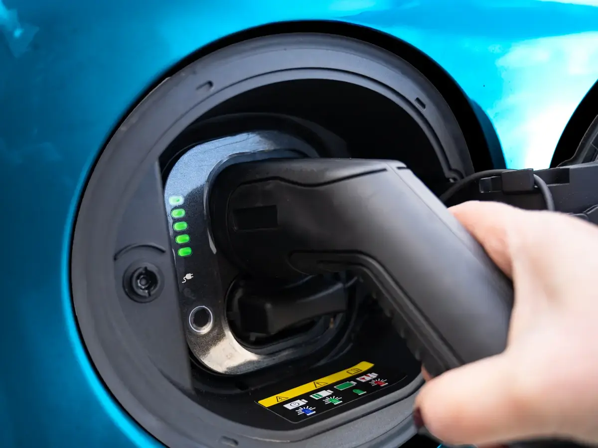 Charging connector being plugged into the charging port of an electric vehicle.