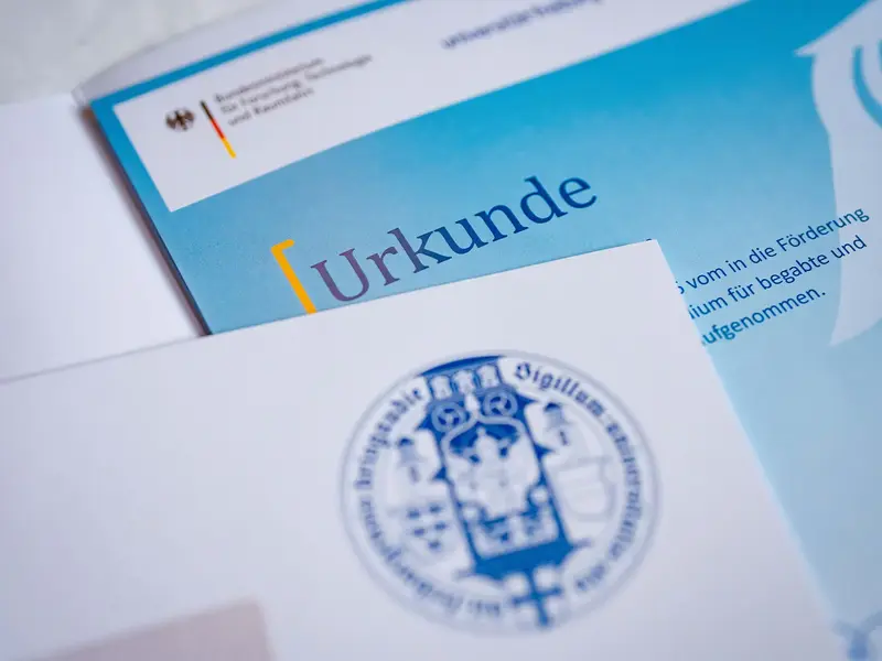 Urkunde und offizielle Dokumente im Kontext von Bildung, Förderung und akademischer Auszeichnung. Die Nahaufnahme symbolisiert Anerkennung von Leistungen, Stipendienprogramme und erfolgreiche Qualifizierung.