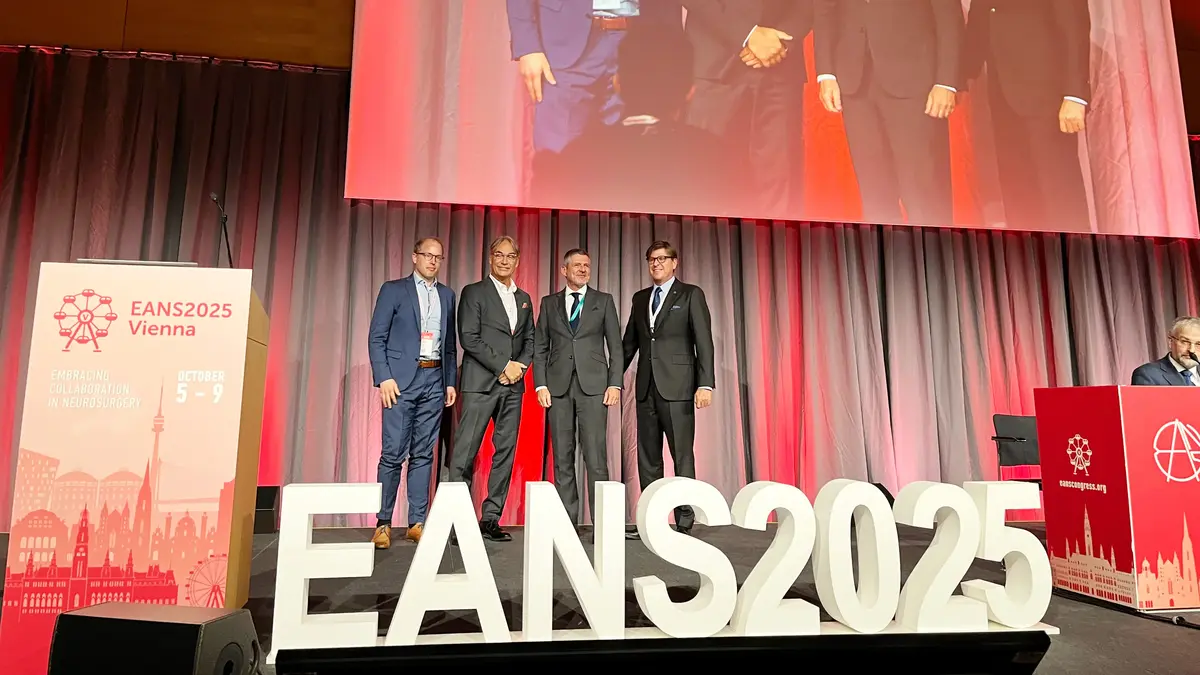 Vier Teilnehmende posieren auf der Bühne des EANS 2025 Kongresses vor einer großen Projektion.