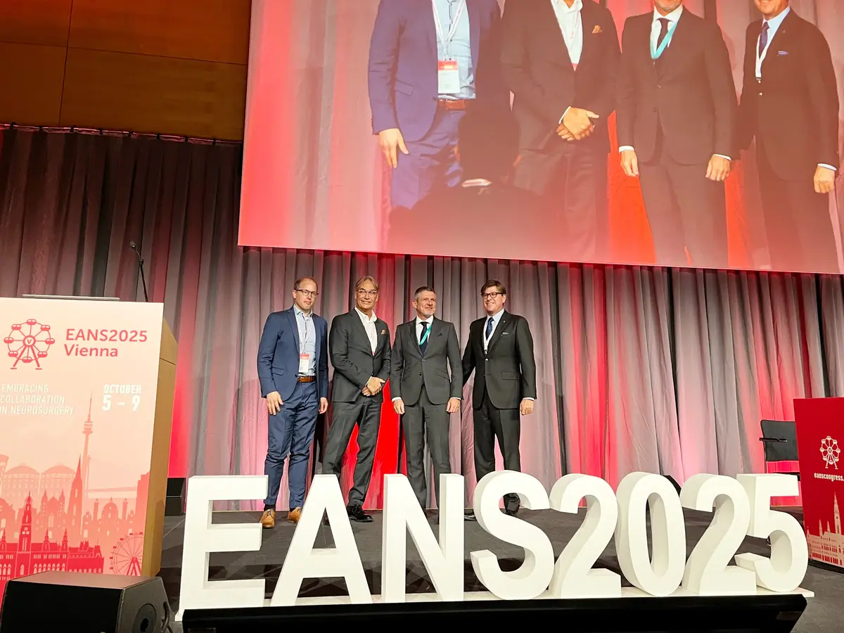 Four participants standing on the EANS 2025 congress stage in front of a large projection screen.