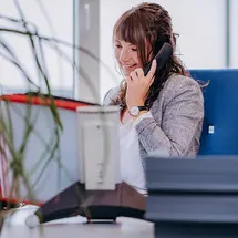 Mitarbeiterin im Vertriebsinnendienst von Sutter Medizintechnik führt ein Telefongespräch im Büro, im Hintergrund sind Unterlagen und Büropflanzen sichtbar.