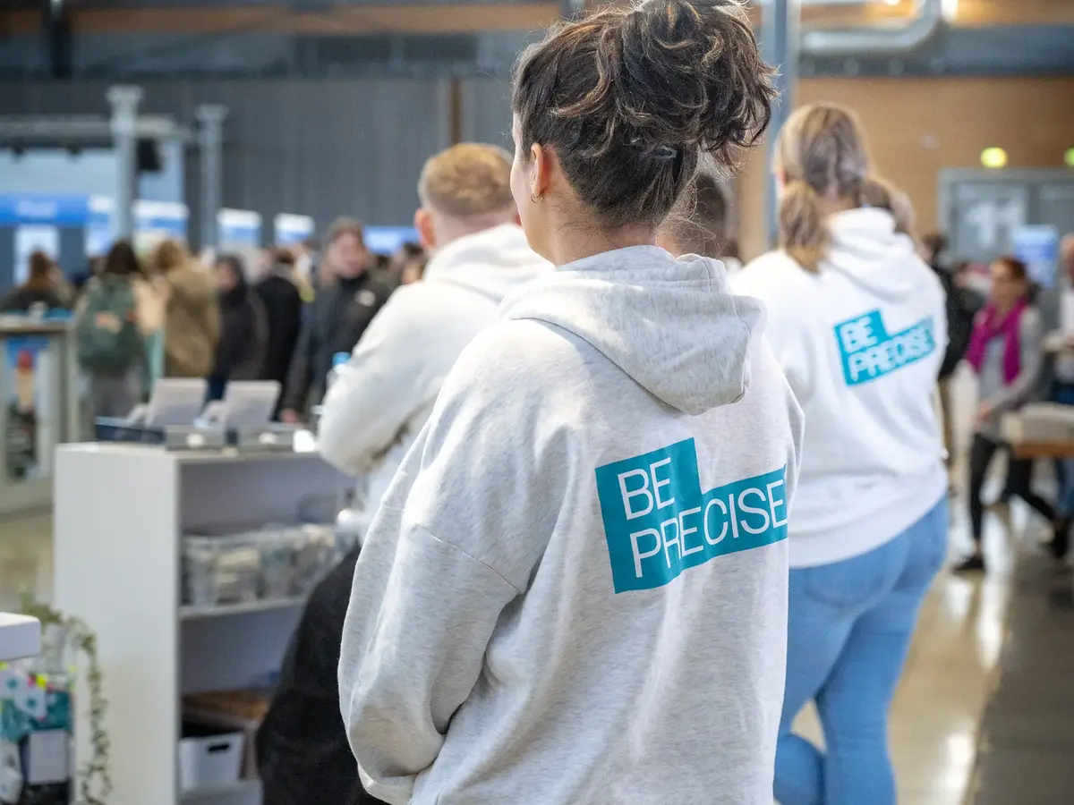 People wearing branded company clothing at a trade fair or industry event.