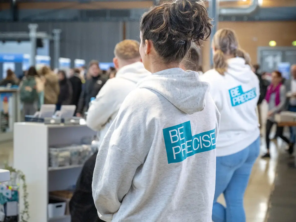 Personen in gebrandeter Unternehmenskleidung auf einer Messe oder Industrieveranstaltung.