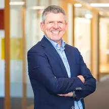 Bert Sutter steht lächelnd mit verschränkten Armen im Büroflur – Geschäftsführer von Sutter Medizintechnik.