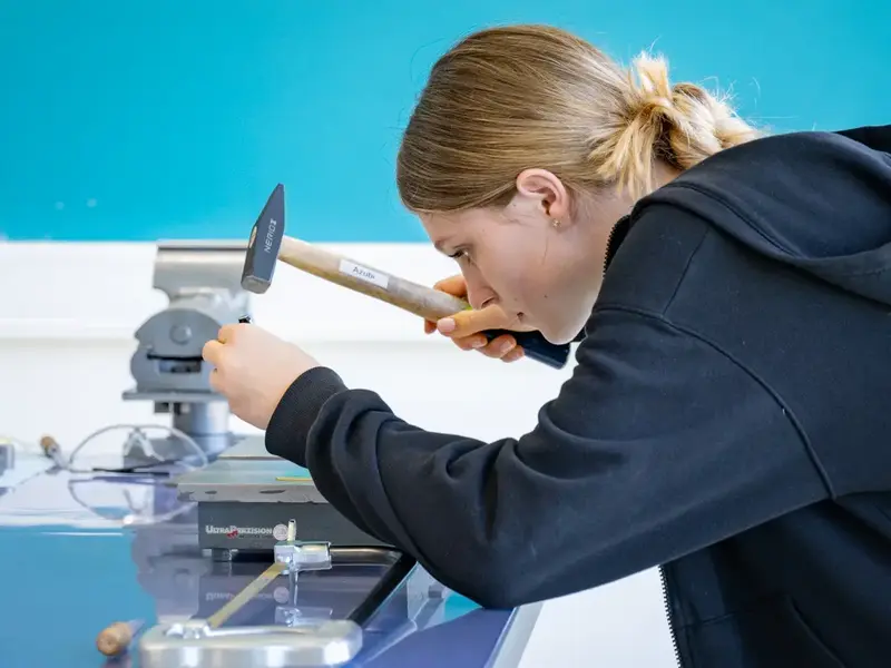 Teilnehmerin bearbeitet ein Werkstück mit einem Hammer bei einer technischen Übung im Rahmen des Girls’ Day.