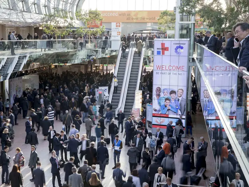 Blick in die Eingangshalle der MEDICA / COMPAMED Messe in Düsseldorf mit zahlreichen Besuchern und Ausstellern – Treffpunkt der internationalen Medizintechnikbranche.