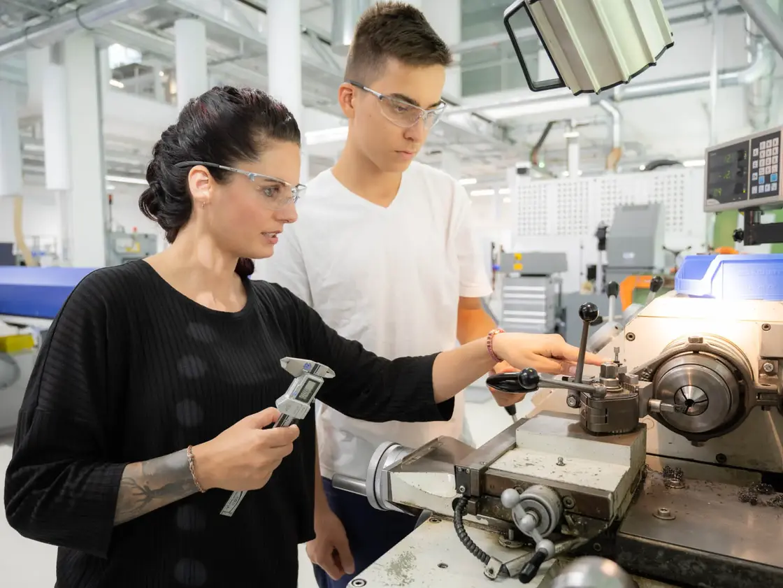 Sutter-Ausbildung-Franziska-Beck-Schulung-2025.jpg Franziska Beck, Ausbilderin bei Sutter Medizintechnik, zeigt einem Auszubildenden die Arbeit an der Drehmaschine – praxisorientierte Ausbildung.