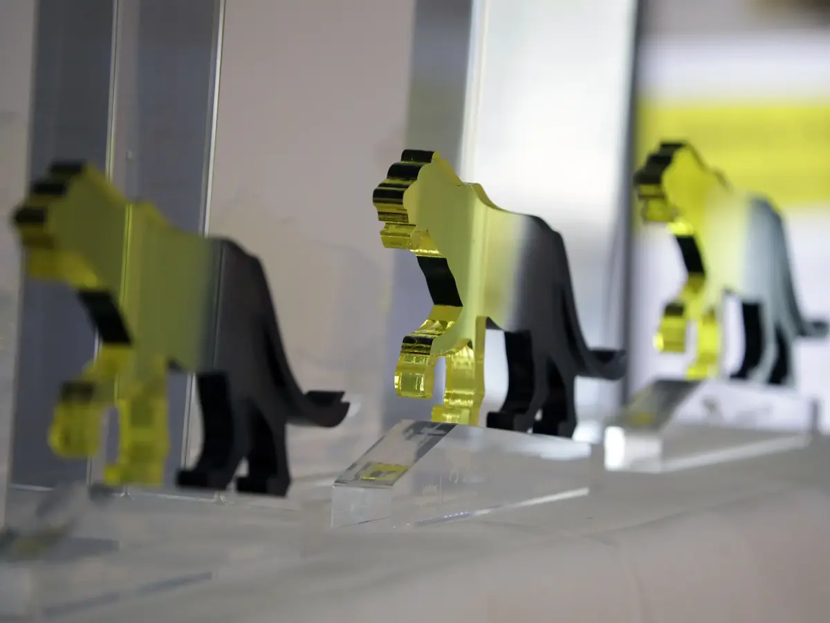 Row of acrylic animal-shaped trophies displayed on transparent bases with blurred background.