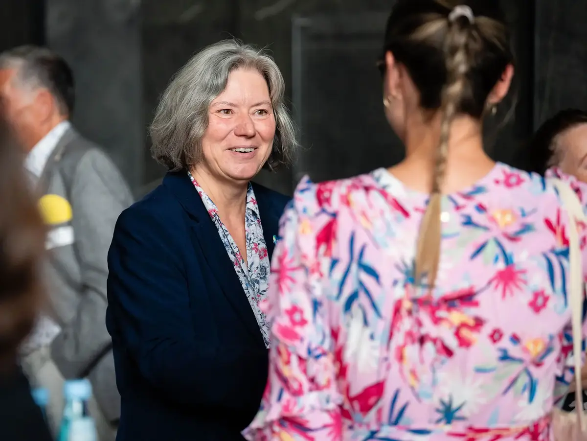 Personal interaction during an academic or networking event. The image highlights conversation, professional exchange, and community building within a university or scholarship-related environment.