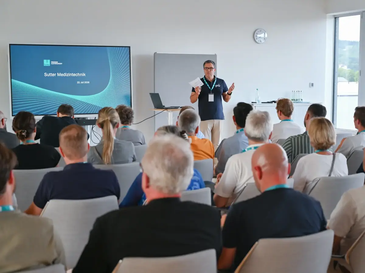 Präsentation bei Sutter Medizintechnik mit Teilnehmenden des Gewerbevereins Emmendingen. Eine Person spricht vor einem Publikum, während auf einem Bildschirm Unternehmensinformationen gezeigt werden.