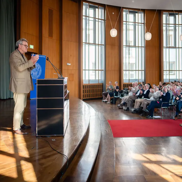 Festveranstaltung des Deutschlandstipendiums an der Universität Freiburg in einem lichtdurchfluteten Hörsaal. Die Aufnahme zeigt einen Redebeitrag vor großem Publikum und unterstreicht die Bedeutung von Bildungsförderung, akademischem Engagement und Nachwuchsentwicklung.