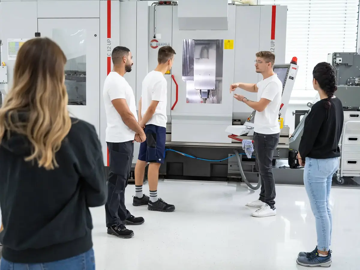 Auszubildende bei Sutter Medizintechnik erhalten eine Einweisung an einer CNC-Fräsmaschine – praxisorientierte Ausbildung in der Feinmechanik.