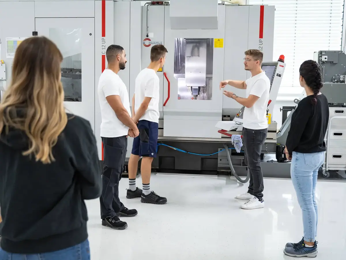 Auszubildende bei Sutter Medizintechnik erhalten eine Einweisung an einer CNC-Fräsmaschine – praxisorientierte Ausbildung in der Feinmechanik.