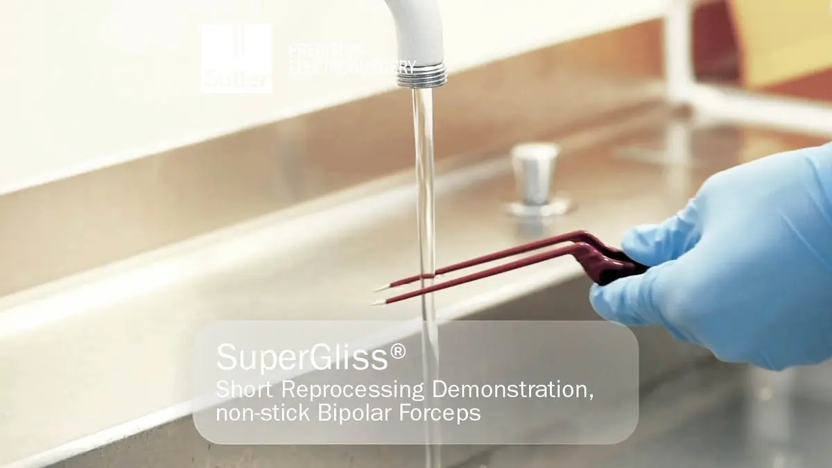 Person mit blauen Handschuhen reinigt SuperGliss® non-stick Bipolare Pinzette unter einem Wasserstrahl in der Sterialisationsabteilung