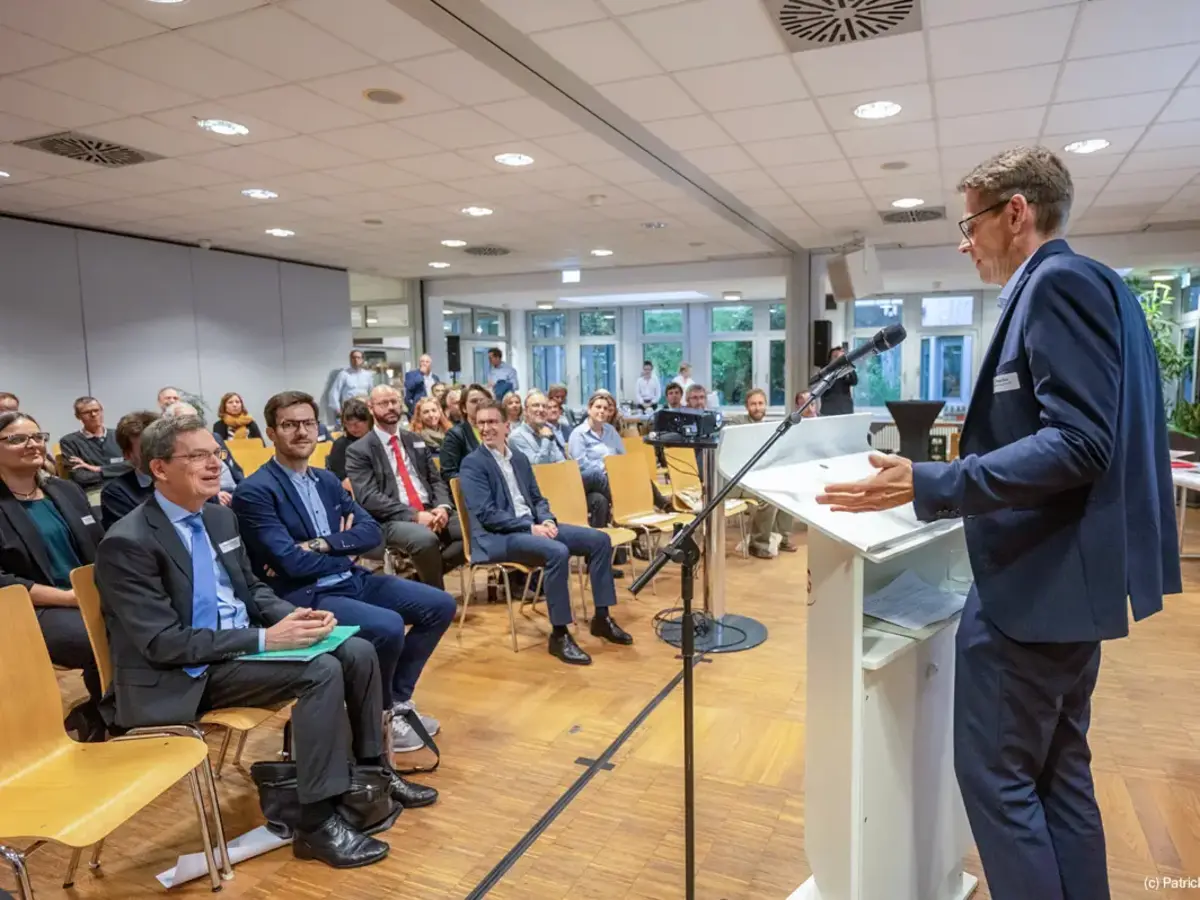 Speaker addressing an audience during a corporate event in a modern conference room.