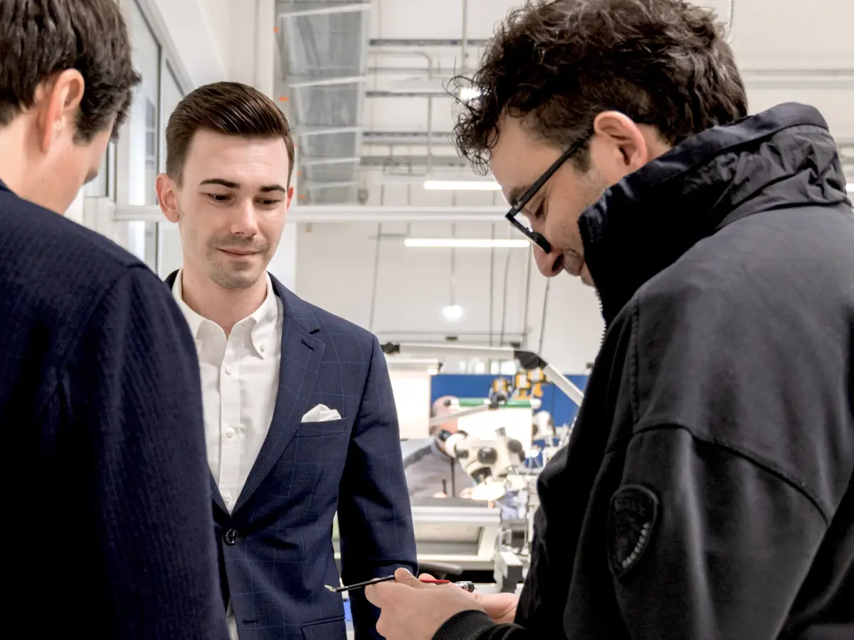 Three people reviewing a technical component in a modern production environment.