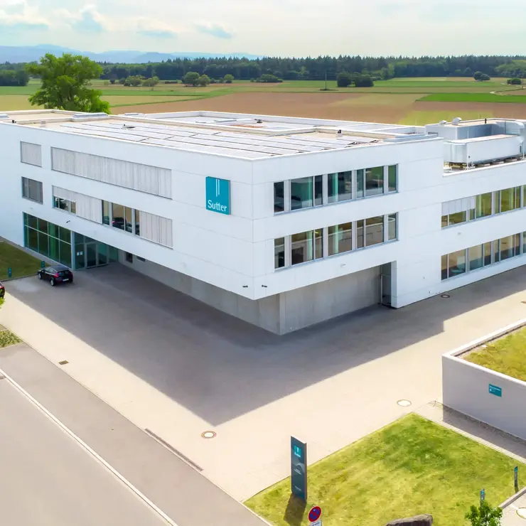 Luftaufnahme des modernen Firmengebäudes von Sutter Medizintechnik in Emmendingen mit Blick auf das Umfeld und angrenzende Felder.        ChatGPT fragen