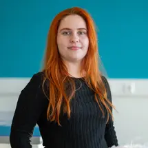 Ausbildungspatin-Sina-Brand.jpg Sina Brand aus der Produktion von Sutter Medizintechnik steht vor einem blauen Hintergrund und schaut freundlich in die Kamera.