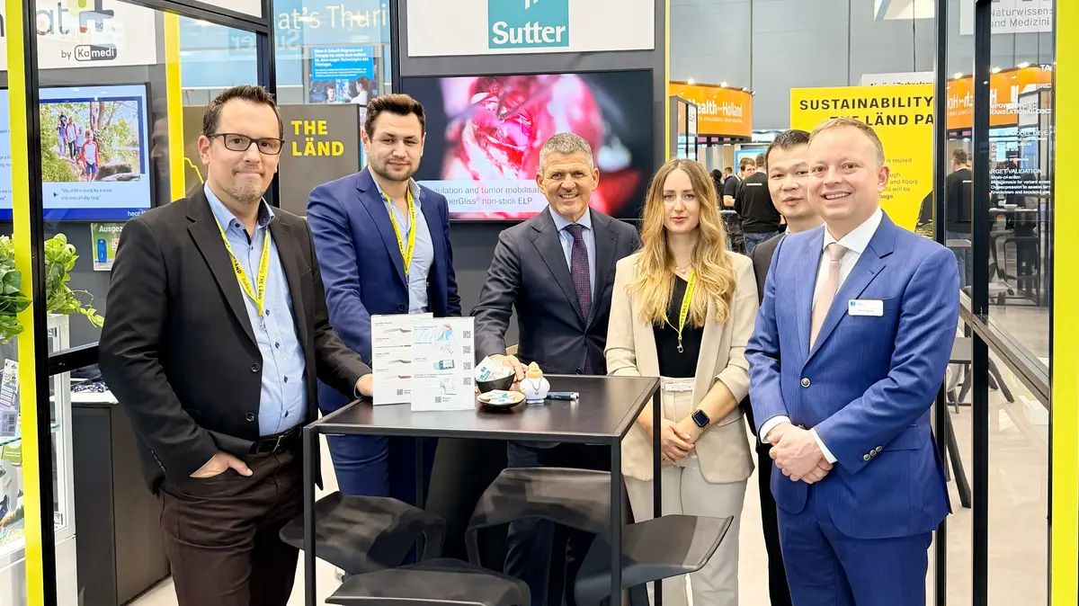 Mehrere Personen an einem Messestand mit Präsentationstisch und Produktmustern auf einer Fachmesse.