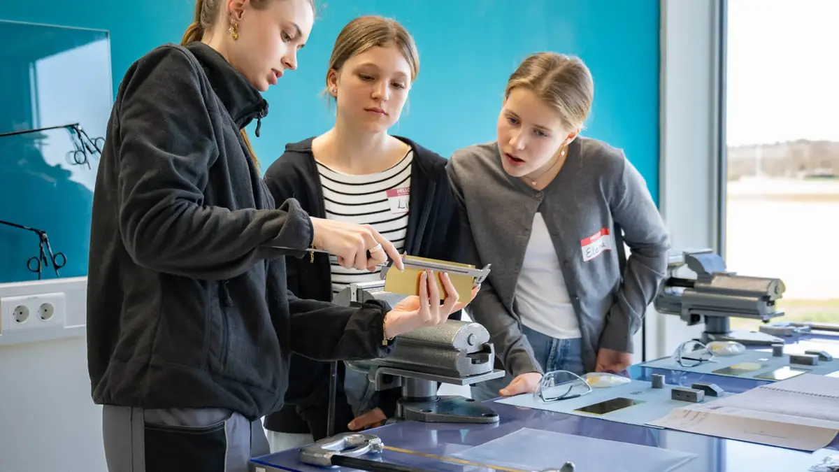 Girls’ Day 2025 bei Sutter Medizintechnik: Eine Auszubildende zeigt Teilnehmerinnen das Feilen und Bearbeiten eines Metallstücks.