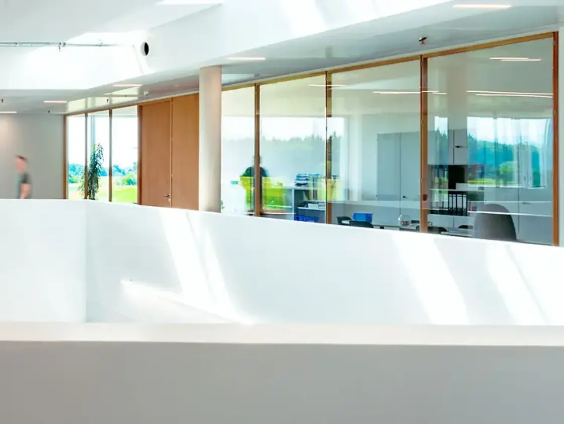sutter-medizintechnik-bueroetage-lichtdurchflutet.jpg Helle Büroetage mit Glasfronten und Durchgangsbereich bei Sutter Medizintechnik, moderner offener Baustil mit Tageslicht.