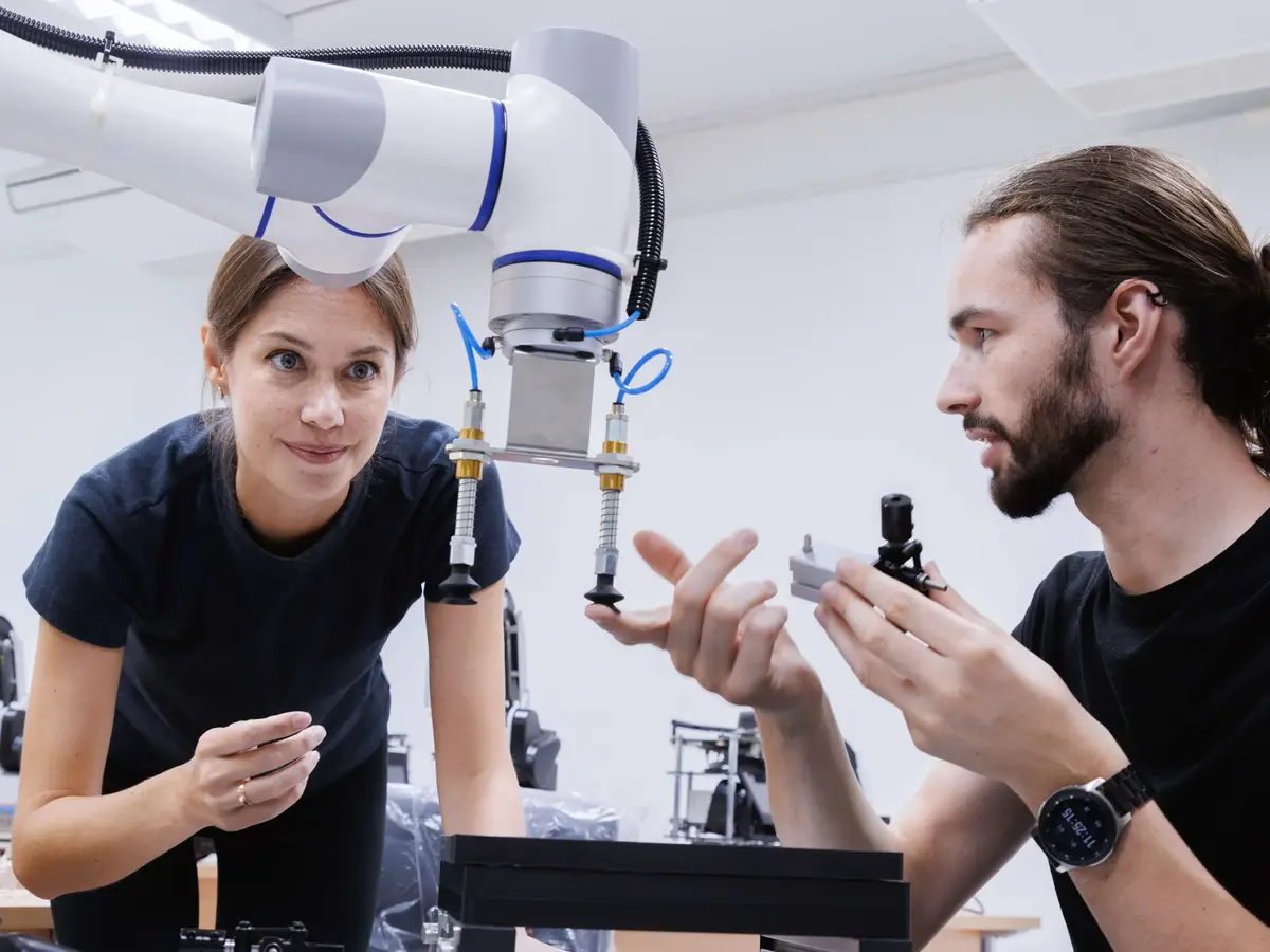 Zwei Fachkräfte prüfen einen kollaborativen Roboterarm in einer Entwicklungsumgebung